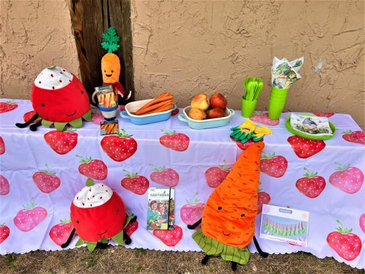 Beispiel Geburtstagstisch Gartenzwerge Gedeckter Geburtstagstisch mit bunten Gemüse- und Obstspielzeugen auf einer Erdbeertischdecke.
