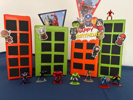 Superhelden Deko Bunte Geburtstagsdeko mit Comicfiguren, darunter Spiderman, vor einem blauen Hintergrund.