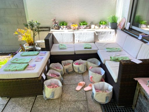 Entspannte Gartensitzgruppe mit Kissen, Fußbädern, Handtüchern und festlicher Spa Party Dekorationen.