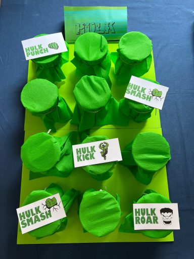 Hulk Spiel Bunte Töpfe mit grünen Abdeckungen und dekorativen Schildern auf einer leuchtend grünen Basis.